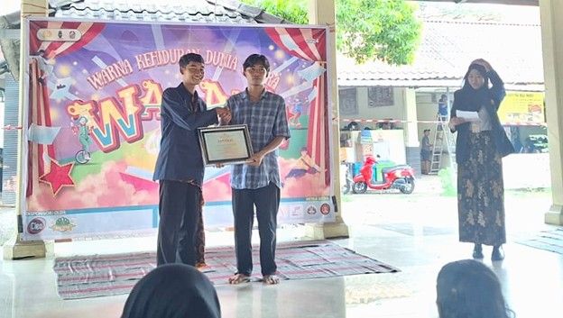 Ketua panitia menyerahkan piagam penghargaan kepada mahasiswa yang menjadi pemantik diskusi.