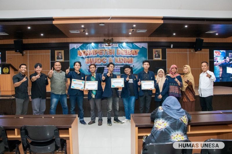 Tim pemenang NUDC foto bersama jajaran dewan juri, dosen pembina, dan pejabat terkait selingkung UNESA. 