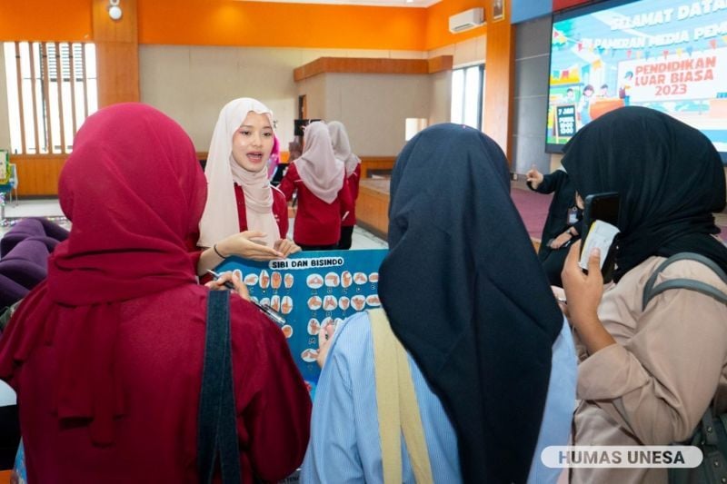 Mahasiswa PLB menjelaskan inovasi media pembelajaran yang mereka rancang kepada pengunjung pameran.