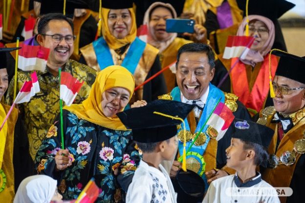 MOMEN LANGKA: Jajaran pimpinan, mitra dan Khofifah Indar Parawansa menyaksikan ekspresi salah satu anak yatim saat dikenakan toga oleh Rektor Cak Hasan.